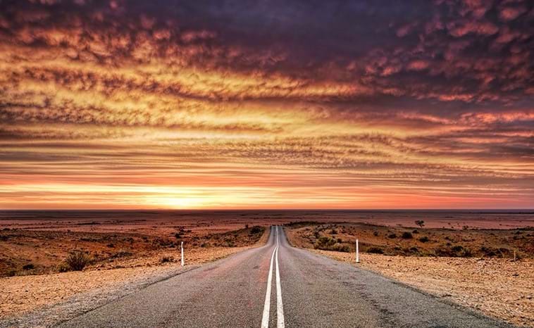 An deserted outback road scene at sunset